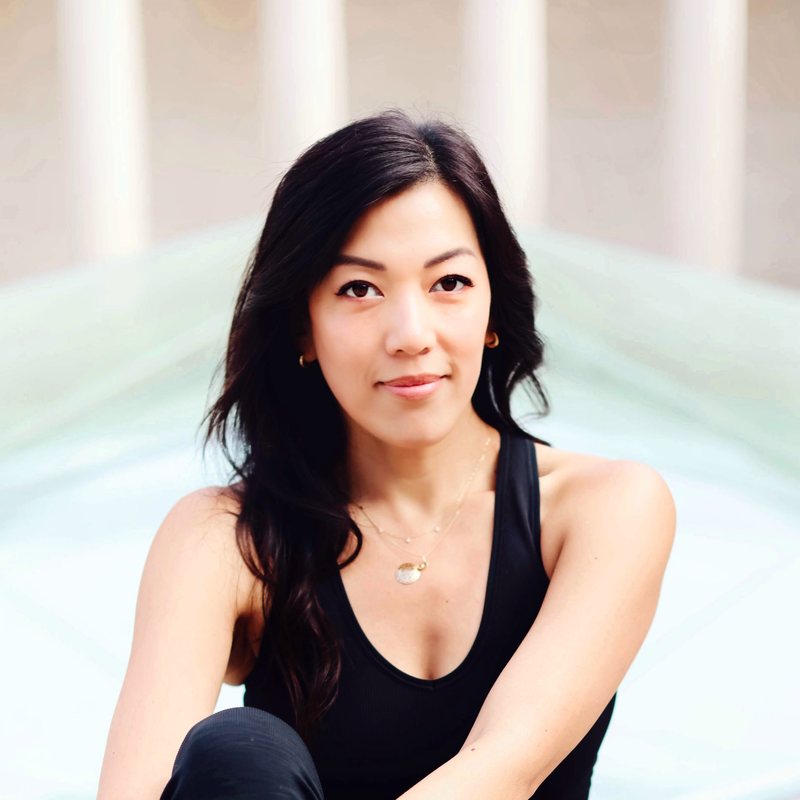 Yvonne Kingsley, vinyasa yoga teacher at The Castro Room in San Francisco, smiling softly, with long dark hair and a black top, in bright light